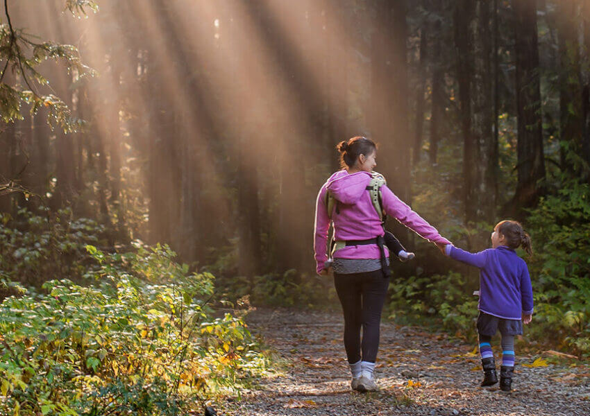 woman and child walking on forest path