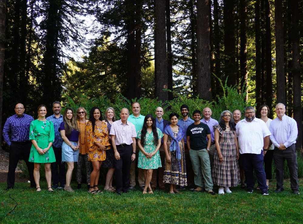 Green Foothills staff and board standing beneath tall trees