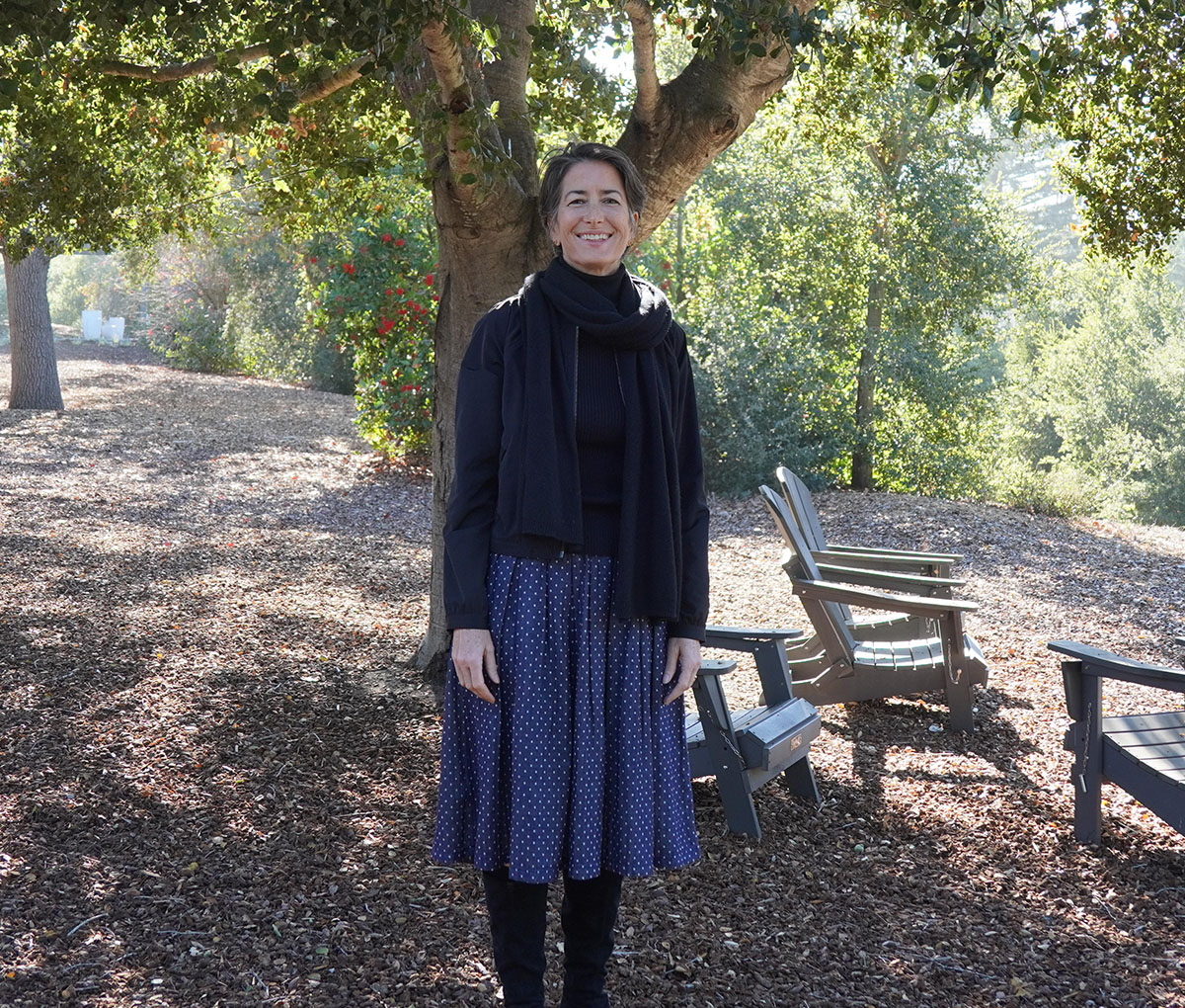 Ash M. standing outdoors among trees