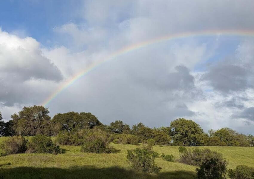Cloudy day over hills with a rainbow